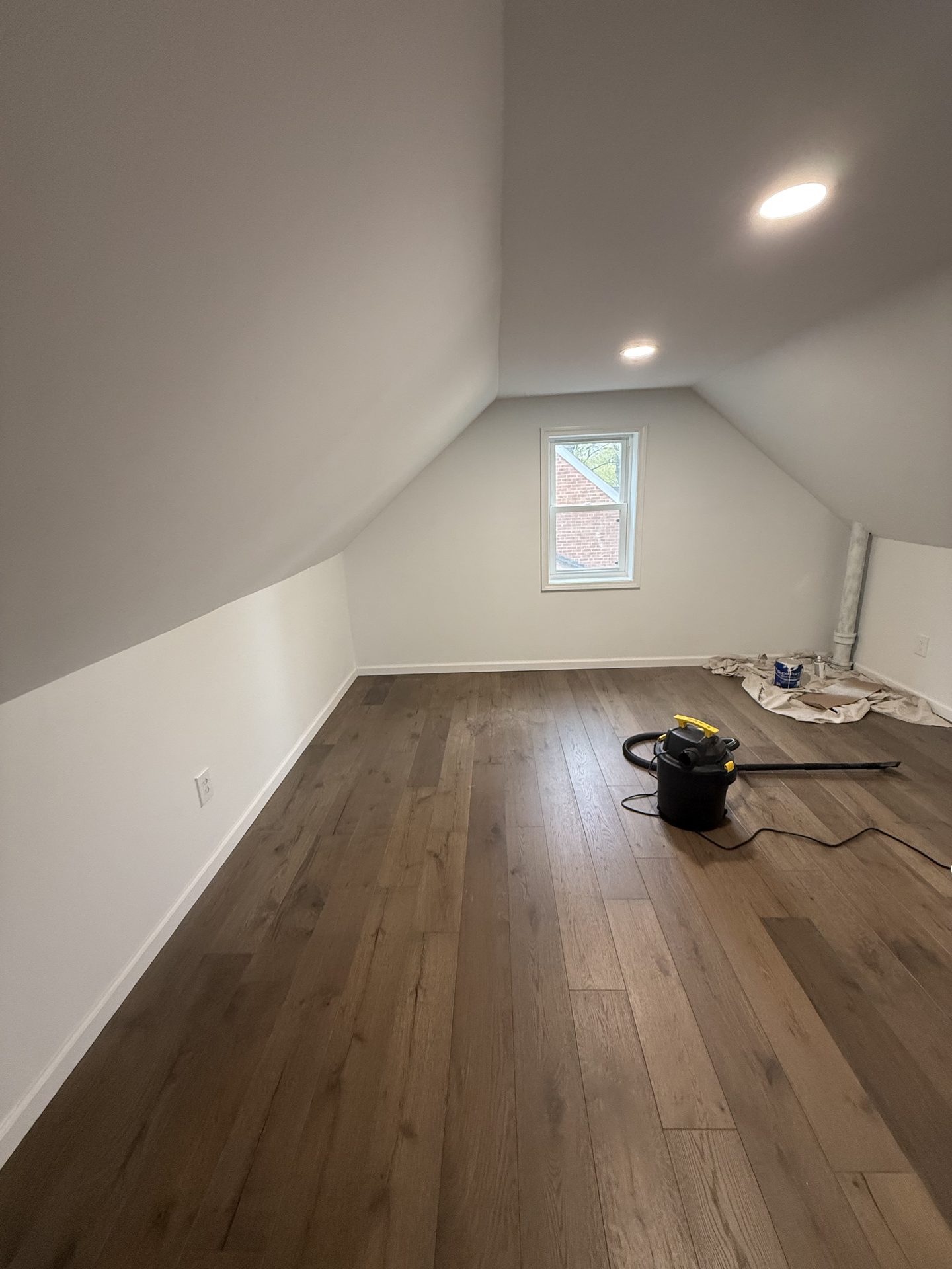 Finished wide-plank hardwood flooring in a renovated attic bonus room